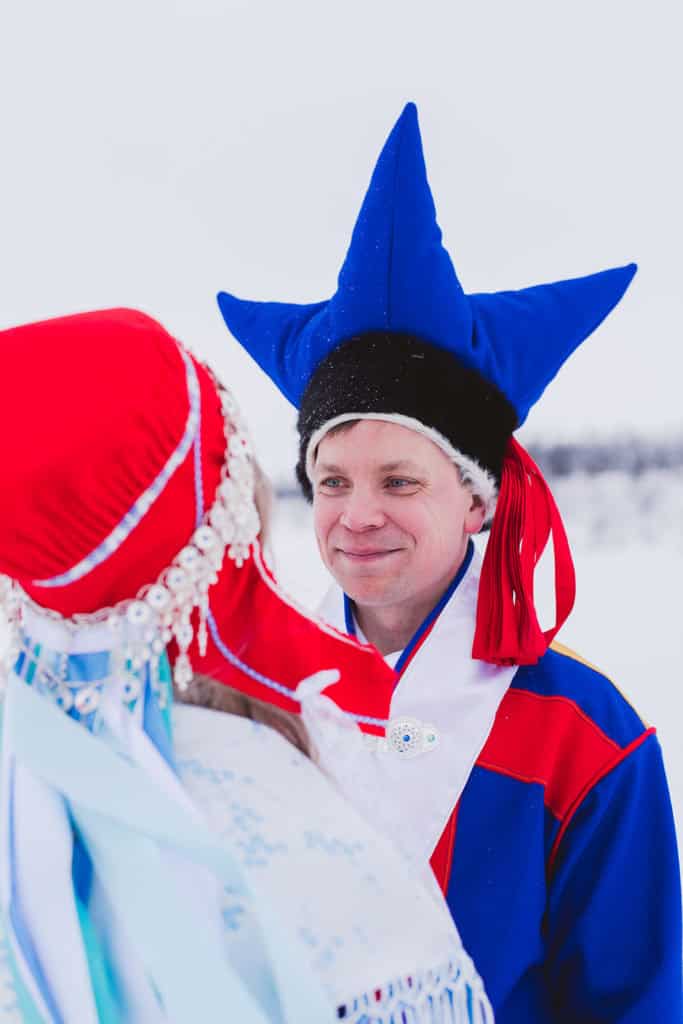 Brudgom fra Karasjok i kofte som står ved hans kone og smiler til henne.